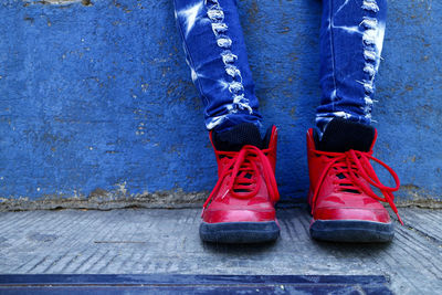 Low section of person wearing red shoes while standing on footpath