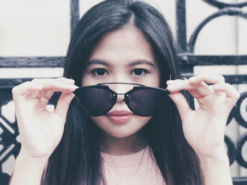 Close-up portrait of young woman holding sunglasses