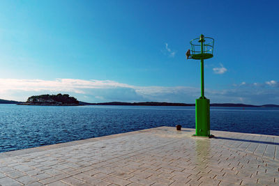 Street light by sea against blue sky