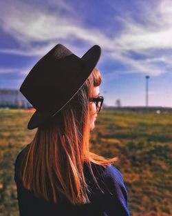 Portrait of woman wearing hat standing on field against sky