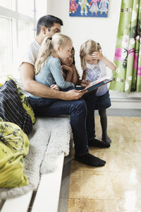 Teacher and girls reading story book in day care center