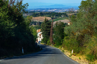 Road amidst trees in city against sky