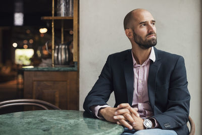 Mid adult businessman looking away white sitting at table in restaurant