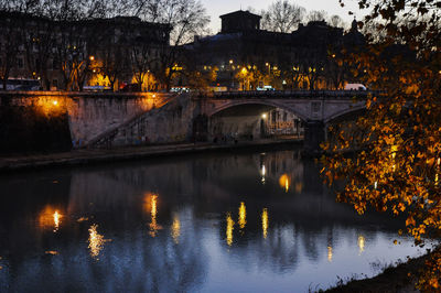 Illuminated bridge over water at night