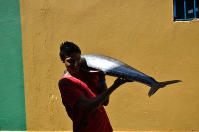 Side view of smiling woman standing against wall