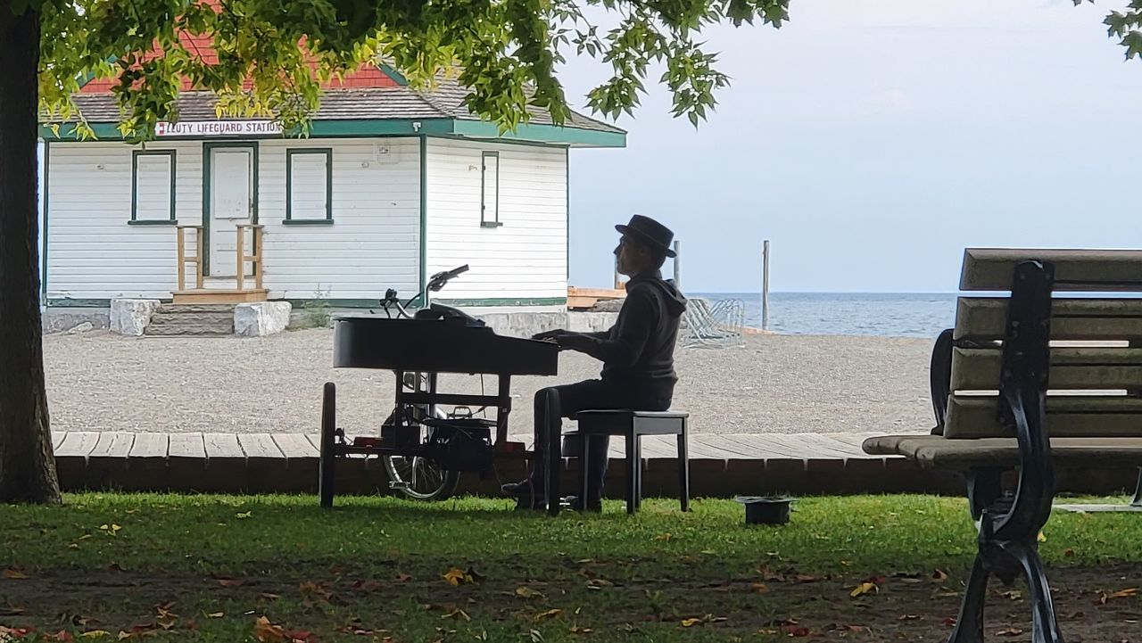 seat, one person, sitting, full length, bench, nature, adult, plant, chair, furniture, leisure activity, water, lifestyles, day, architecture, men, relaxation, casual clothing, side view, outdoors, home, tree, sky, music, house, grass, women, musical instrument, built structure, young adult