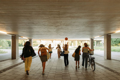 Rear view of teenage girls walking together under bridge