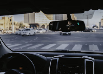 Man wearing sunglasses driving car reflecting in mirror