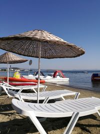 Deck chairs on beach against clear sky