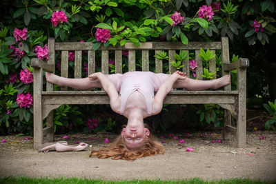 Low section of person lying on bench against pink flowers