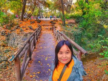 Portrait of smiling young woman on footbridge during autumn