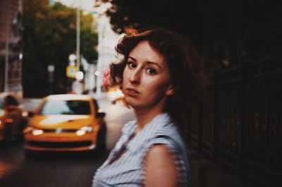 Portrait of young woman standing on street in city