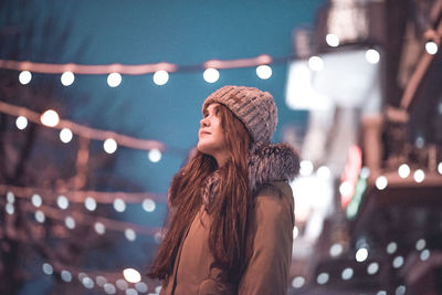 Woman looking away while standing at night