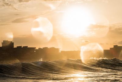 Seascape in city against sky during sunset