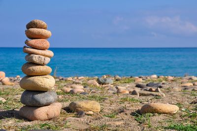 Stack of stones on beach against sky