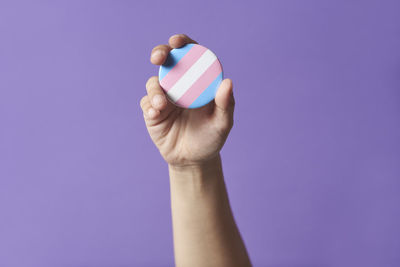 Cropped hand of woman holding condom against blue background