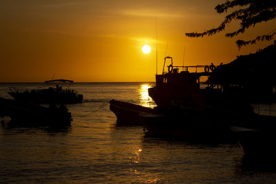 Silhouette boat in sea against sky during sunset