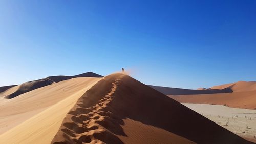 Scenic view of desert against clear blue sky