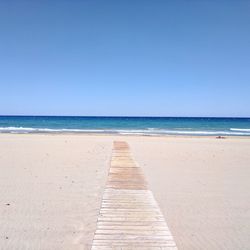 Scenic view of beach against clear blue sky