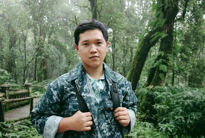 Portrait of young man standing in forest