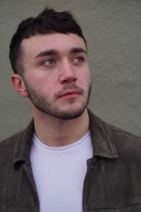 Close-up of young man looking away against wall