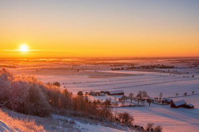 Scenic view of snow covered field against sky during sunset