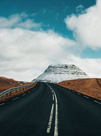 Empty road by mountain against sky