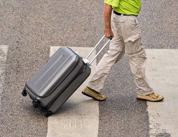 Low section of man with suitcase on street