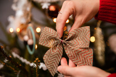 A woman in a red sweater improves a bow hung on a christmas tree.