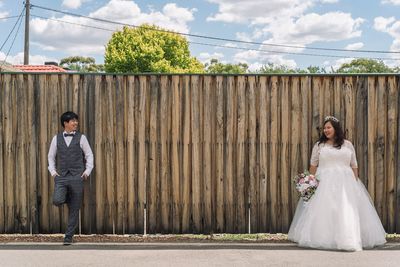 Portrait of young couple standing against wall