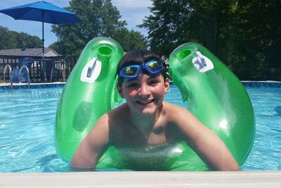 Portrait of smiling boy with inflatable ring in swimming pool