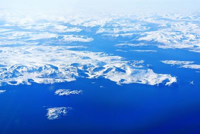 Aerial view of snow covered landscape against blue sky