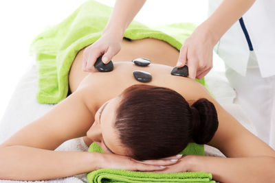 High angle view of woman having lastone therapy while lying down on bed