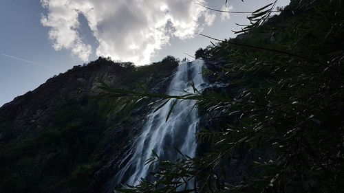 Scenic view of waterfall in forest against sky