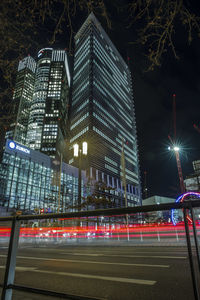 Light trails on road by buildings in city at night