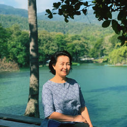 Portrait of young woman sitting by lake