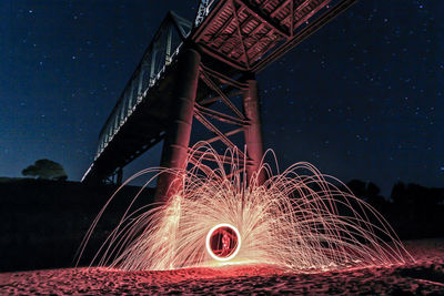 Person light painting under bridge at night