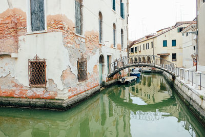 Arch bridge over canal amidst buildings in city