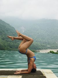 Midsection of woman with arms raised on mountain