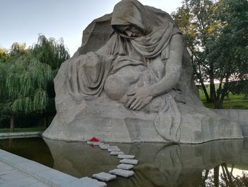 Statue by tree against sky