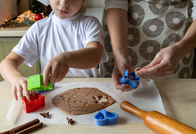 Midsection of woman with daughter preparing food at home