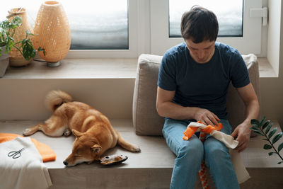 Adult man making diy homemade educational toys for dogs using a tutorial from the internet