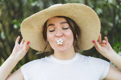 Young funny beautiful woman in a hat among flowering trees. breathe free. happy woman no allergy