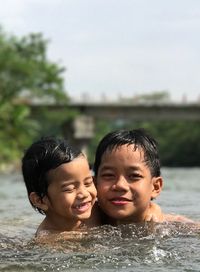 Close-up portrait of smiling boy with water against sky