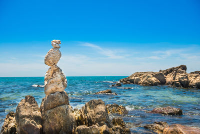 Scenic view of rocks on beach against blue sky