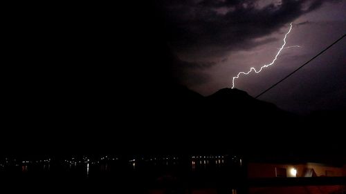 Silhouette of city against dramatic sky at night