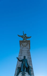 Low angle view of statue against blue sky