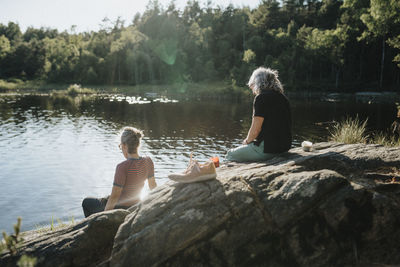 Two senior women sitting on rock at lakeshore