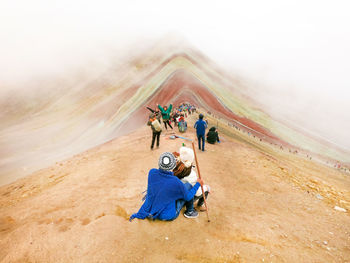 Rear view of people sitting on multi colored mountain