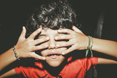 Close-up of boy covering eyes with finger